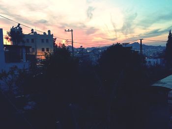 Silhouette buildings against sky at sunset