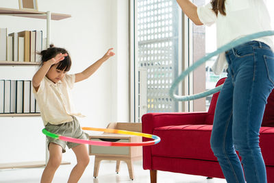 Midsection of mother and daughter playing with plastic hoops at home