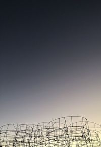 Low angle view of silhouette crane against clear sky