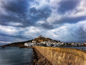 Buildings by sea against sky in city