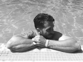 High angle view of young man looking away while relaxing in swimming pool