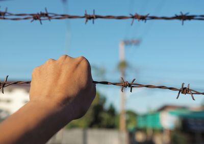 Close-up of barbed wire fence against sky