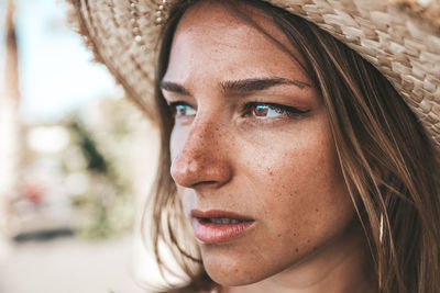 Close-up of young woman wearing hat looking away
