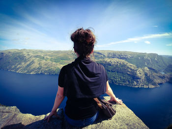 Rear view of man looking at mountains against sky