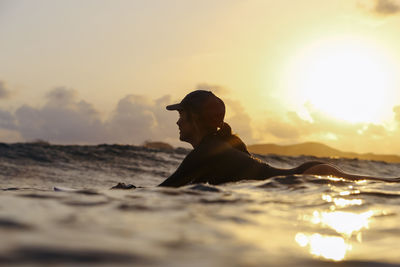 Female surfer lying on surfboard in the evening