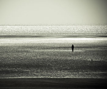 Silhouette of person standing in the middle of the sea