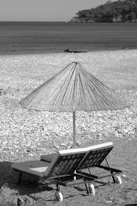 Deck chairs on beach against sky