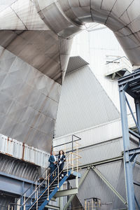 Businessman standing with colleague on staircase at power station