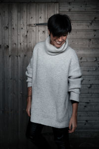 Portrait of smiling young woman standing against wall