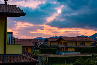 Houses in town against sky during sunset