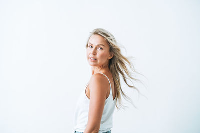 Portrait of young woman standing against white background