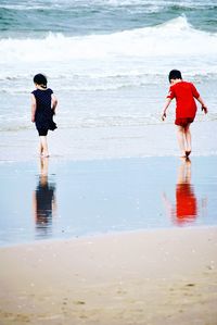 Rear view of people enjoying at beach
