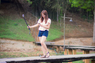 Woman using mobile phone while walking on footbridge