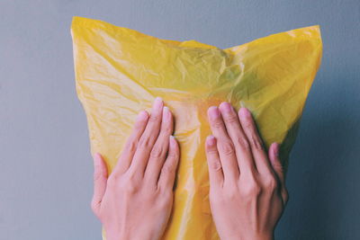 Close-up of hands against yellow background