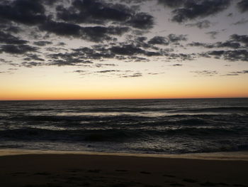 Scenic view of beach against sky at sunset