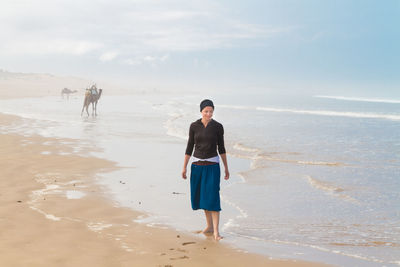 Full length of woman standing on beach against sky