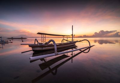 Boat moored in sea against sky during sunset