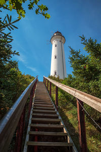 Low angle view of lighthouse amidst trees and buildings against sky