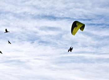 Low angle view of person paragliding against cloudy sky