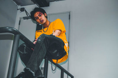 Portrait of smiling young man sitting on wall
