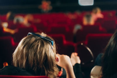 Rear view of woman with friend sitting at theater