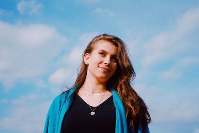 Portrait of beautiful young woman standing against sky