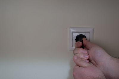 Close-up of person holding hands against white wall