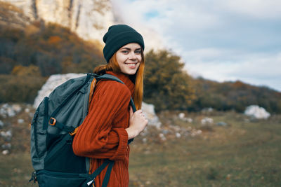 Portrait of smiling young woman wearing hat standing outdoors