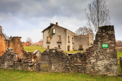 Old building by trees on field against sky