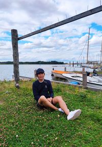 Portrait of young woman sitting on land against sky