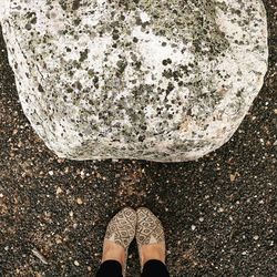 Low section of woman standing by rock