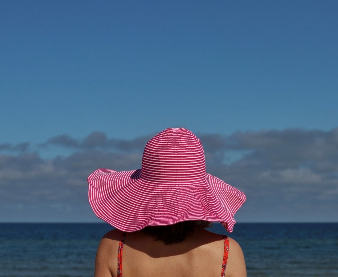 sea, hat, sky, water, one person, real people, leisure activity, beach, lifestyles, day, clothing, land, beauty in nature, nature, sun hat, horizon over water, adult, women, outdoors, body part, hand