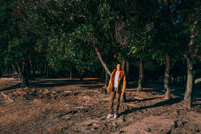 Man standing on field against trees in forest