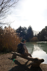 Side view of man sitting on rock against sky