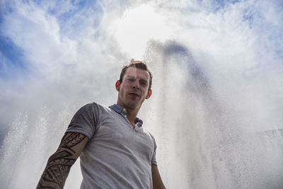 Portrait of man standing against splashing water