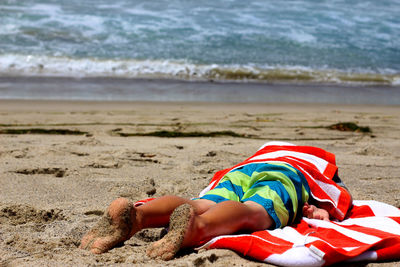 Man with towel lying on front at beach