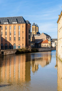 Buildings by river against sky