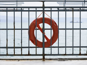 Red railing by sea against sky