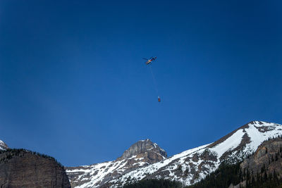 Low angle view of ski lift against clear blue sky