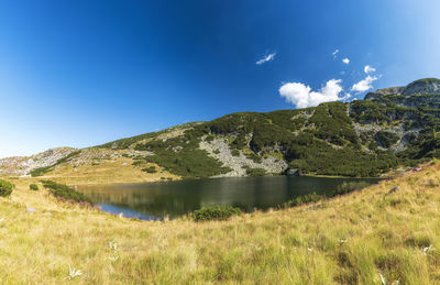 Scenic view of lake and mountains against blue sky