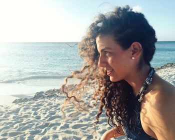 Portrait of young woman at beach against clear sky