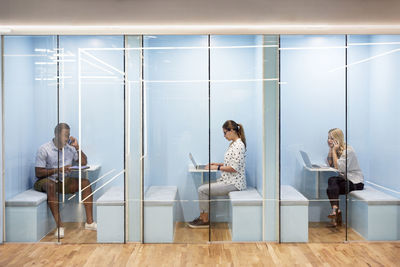 Multi-ethnic business people using laptops while sitting in cubicles at office