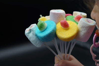 Close-up of hand holding ice cream cone against black background