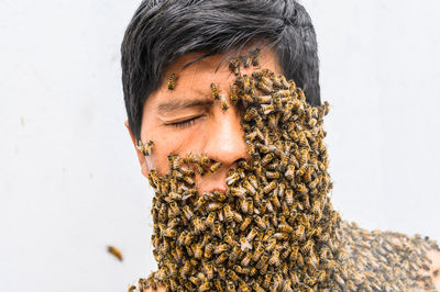 Man's face covered by bees