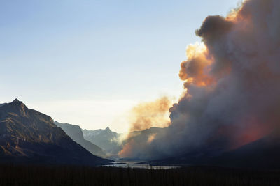 Smoke emitting from glacier national park during sunset against clear sky