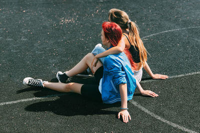 Teenage girls are sitting on a sports field in a park or a school stadium. friends, friendship