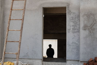 Rear view of man sitting against building