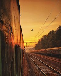 Railroad tracks against sky at sunset