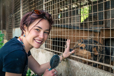 Dog at the shelter.  lonely dogs in cage with cheerful woman volunteer