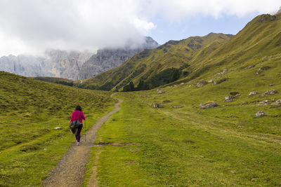Rear view of man walking on mountain against sky